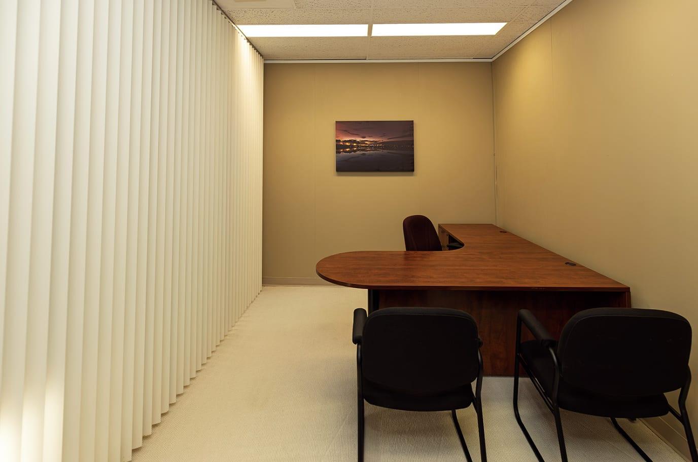 A private office with an L-shaped desk and two guest chairs